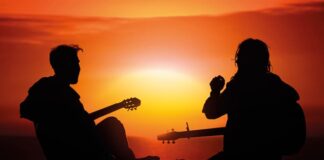 Vuelve a tener un lugar Dos jóvenes con guitarras al atardecer, símbolo del resurgir espiritual y católico entre las nuevas generaciones