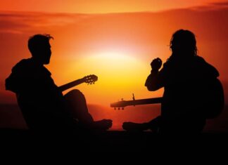 Vuelve a tener un lugar Dos jóvenes con guitarras al atardecer, símbolo del resurgir espiritual y católico entre las nuevas generaciones