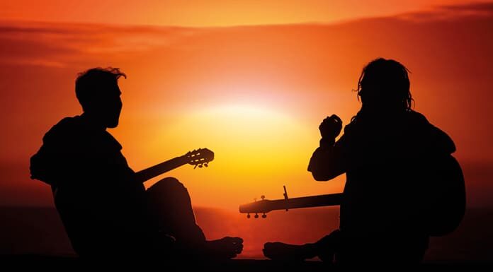 Vuelve a tener un lugar Dos jóvenes con guitarras al atardecer, símbolo del resurgir espiritual y católico entre las nuevas generaciones