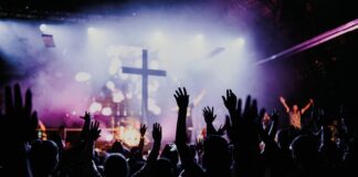 Dios, a la moda Jóvenes con los brazos en alto durante un concierto, símbolo de búsqueda colectiva y emoción compartida
