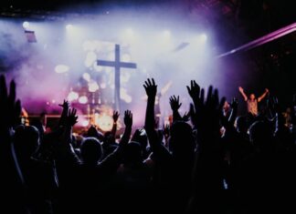 Dios, a la moda Jóvenes con los brazos en alto durante un concierto, símbolo de búsqueda colectiva y emoción compartida