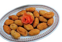 Croquetas de langostinos Fuente de croquetas de langostinos caseras recién fritas, acompañadas de ensalada mixta con lechuga, tomate y aceitunas negras