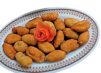 Croquetas de langostinos Fuente de croquetas de langostinos caseras recién fritas, acompañadas de ensalada mixta con lechuga, tomate y aceitunas negras