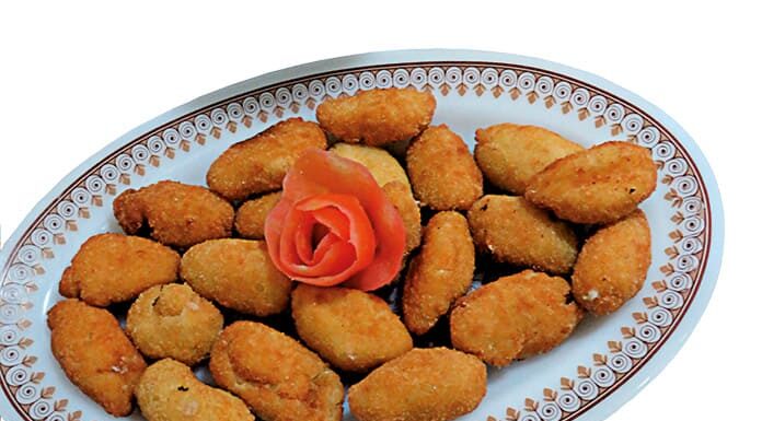 Croquetas de langostinos Fuente de croquetas de langostinos caseras recién fritas, acompañadas de ensalada mixta con lechuga, tomate y aceitunas negras